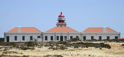 Fyrtårnet på Cabo Sardao med rødt lyshus og hvite bygninger over den vindblåste klippeheia på Alentejokysten