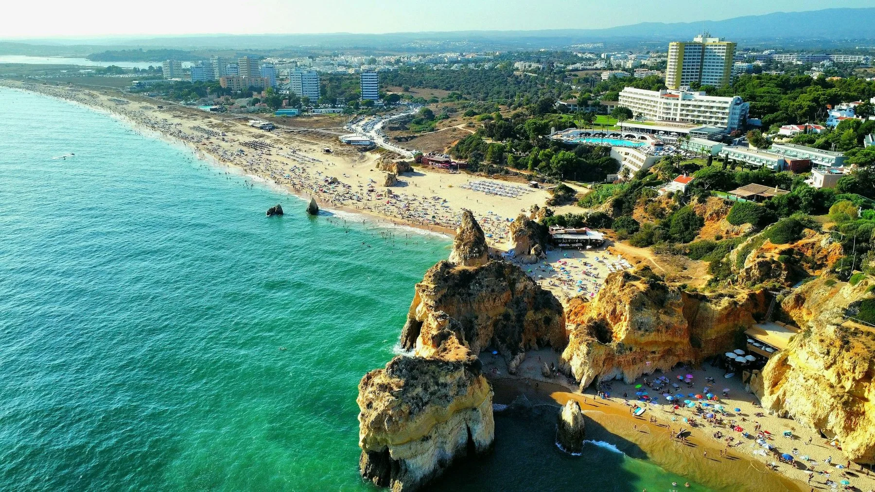 Luftfoto av den brede stranden ved Praia da Rocha med klippene og hoyhusene bak