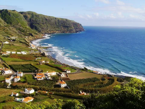 Praia Formosa på Santa Maria sett fra utsiktspunktet, med hvite hus, grønne åkerlapper og bølger mot sanden