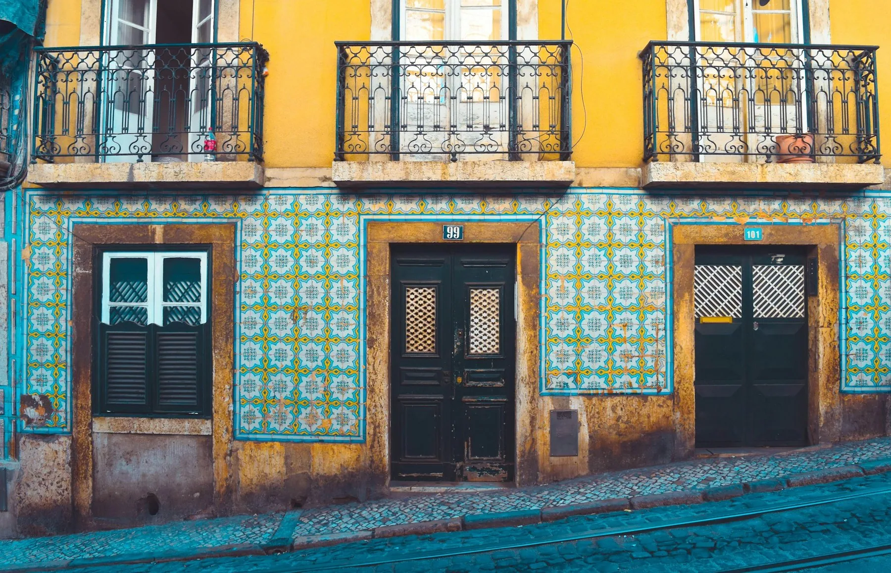 Beige og hvitt toetasjes hus med tradisjonell portugisisk fasade i en gate i Lisboa