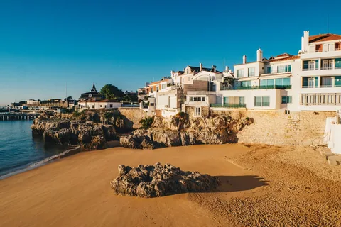 Hvit bygning på de brune klippene ved sjøkanten i Cascais utenfor Lisboa