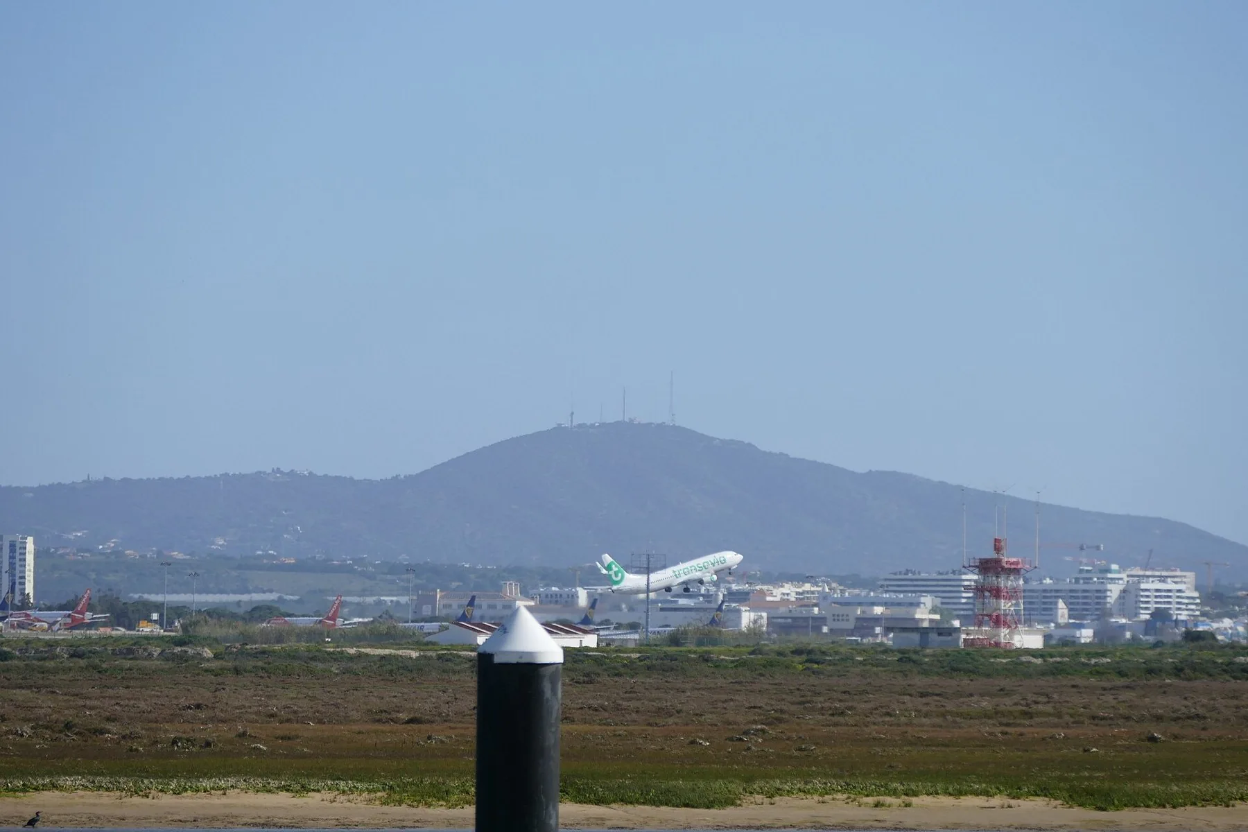 Et fly letter fra Faro lufthavn over våtmarkene i Ria Formosa, med fjellet Cerro de São Miguel bak