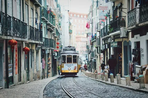 Trikk på vei mellom bygårdene i en smal gate ved Rossio i Lisboa sentrum