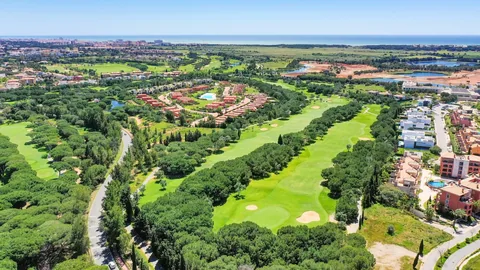 Golfbane i Vilamoura sett fra luften, med fairwayer mellom pinjetrær og havet i det fjerne