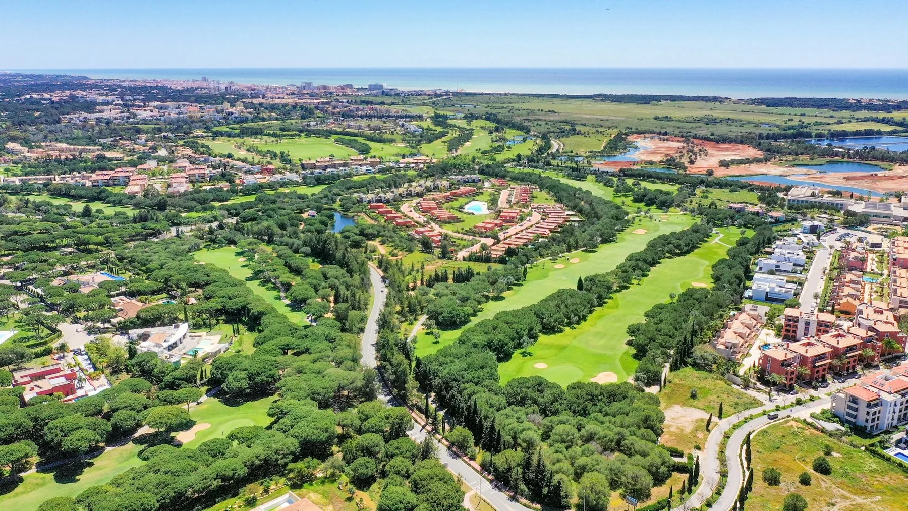 Dronebilde over golfbanen i Vilamoura med grønne fairwayer, vann og villaer mot Algarve-kysten