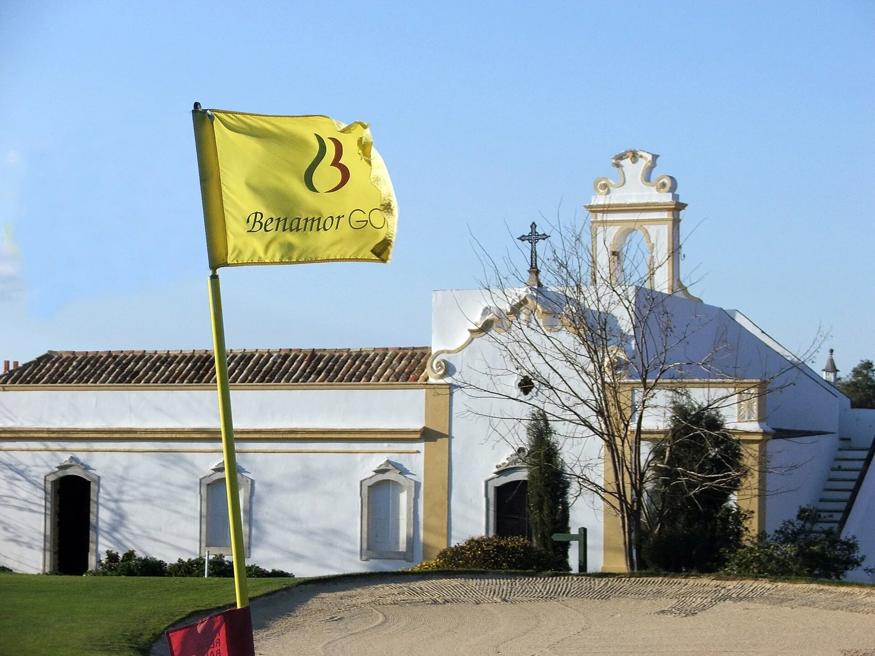 Gult hullflagg på 18. green foran det hvitkalkede kapellet ved klubbhuset på Benamor-banen ved Tavira