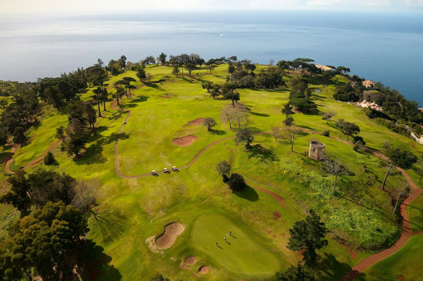 Golfbanen Palheiro høyt over Funchal sett fra luften, med fairwayer, bunkere og havet i bakgrunnen