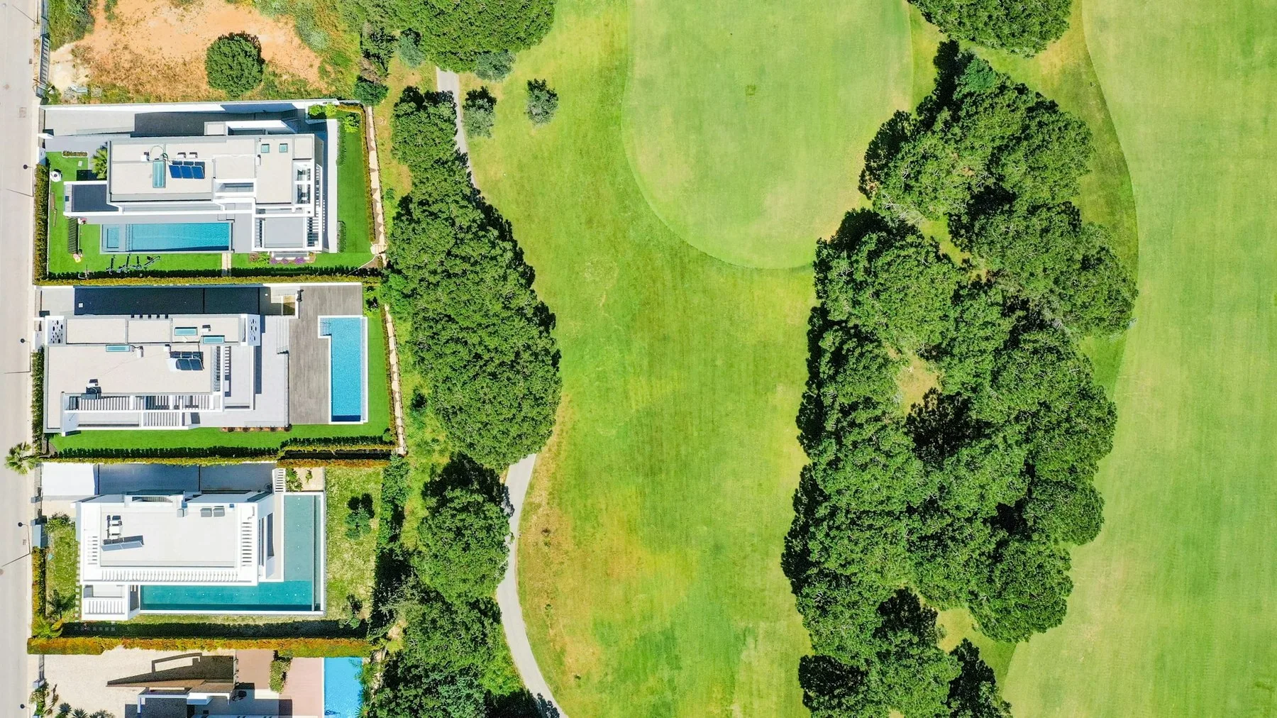 Villaer med basseng langs en grønn fairway i Vilamoura, sett rett ovenfra