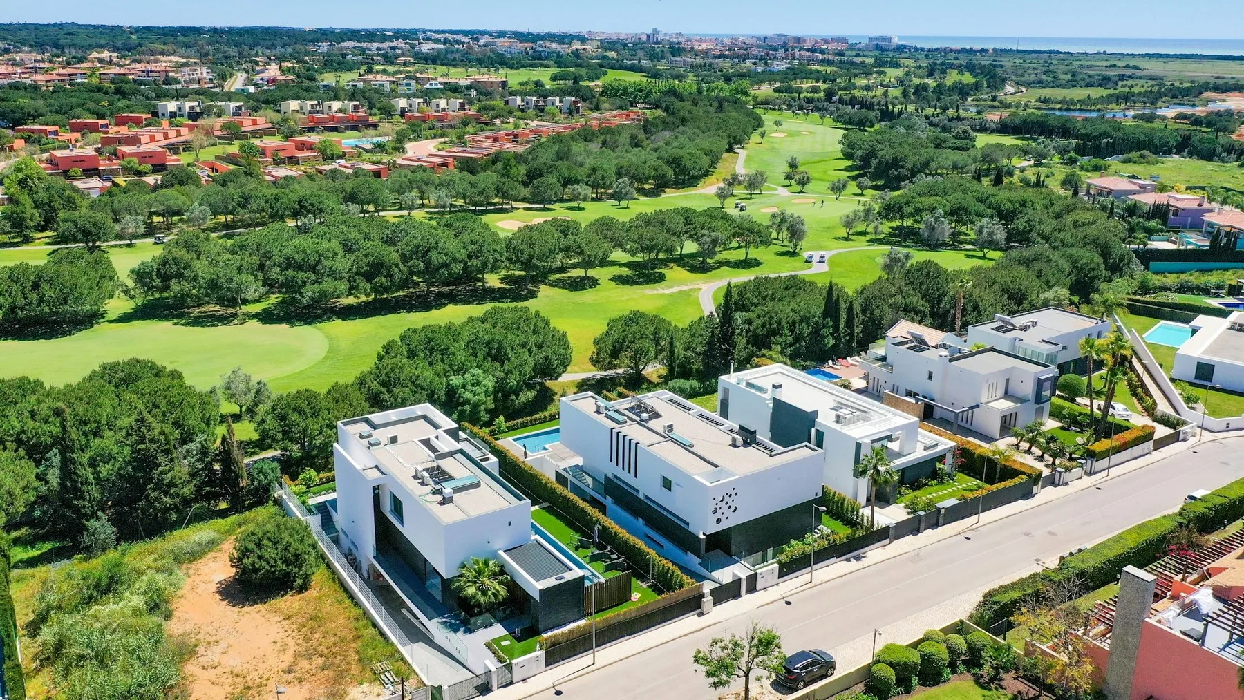 Fugleperspektiv over grønne golfhull og lave hvite hus i Vilamoura i Algarve