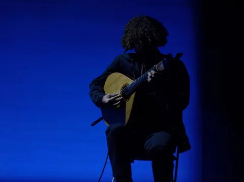 Fadomusiker i silhuett med portugisisk gitar mot dypblått scenelys