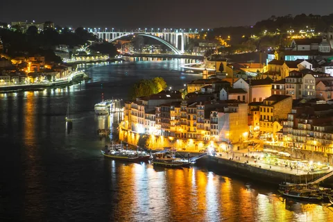 Ribeira i Porto om natten med opplyste hus langs Douro og Arrábida-broen i bakgrunnen