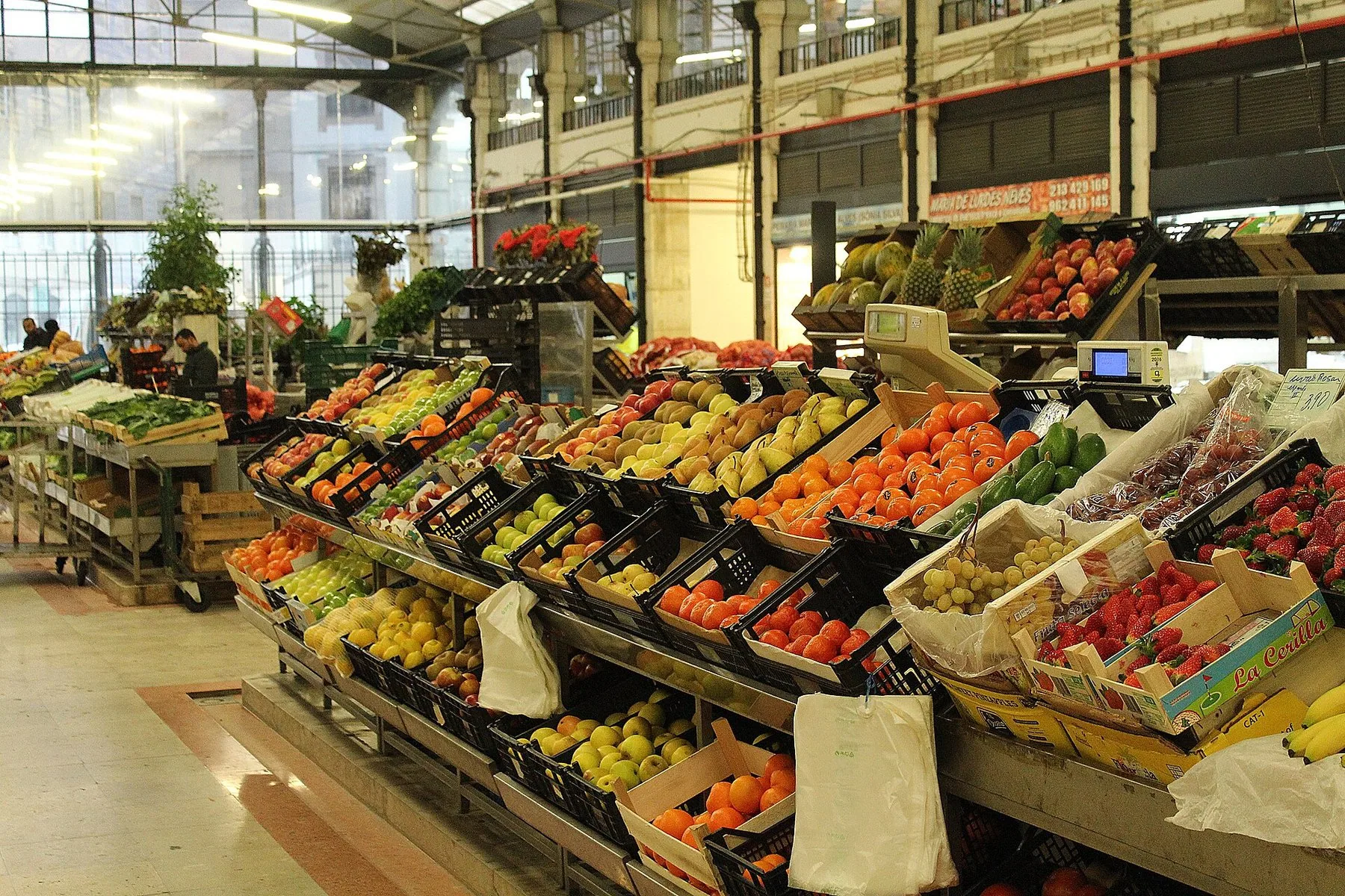 Fruktdisker med appelsiner, epler og pærer i kasser under jernkonstruksjonen i Mercado da Ribeira