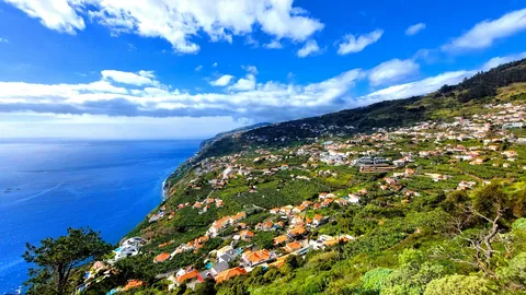 Arco da Calheta med hus og terrasser i den bratte, grønne fjellsiden mot havet