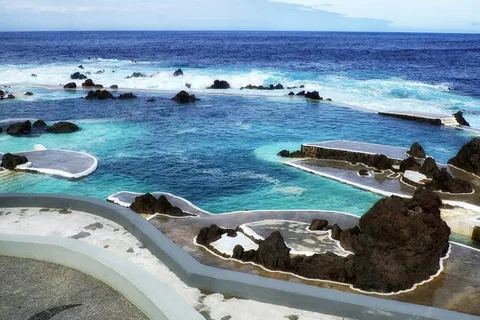 Naturbassengene i Porto Moniz omgitt av svart lavastein, med Atlanterhavet utenfor
