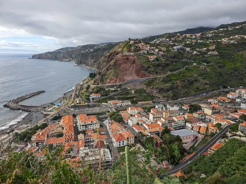 Ribeira Brava sett fra utsiktspunkt: rødtakte hus i dalbunnen, molo ved havet og bratte terrasserte fjellsider