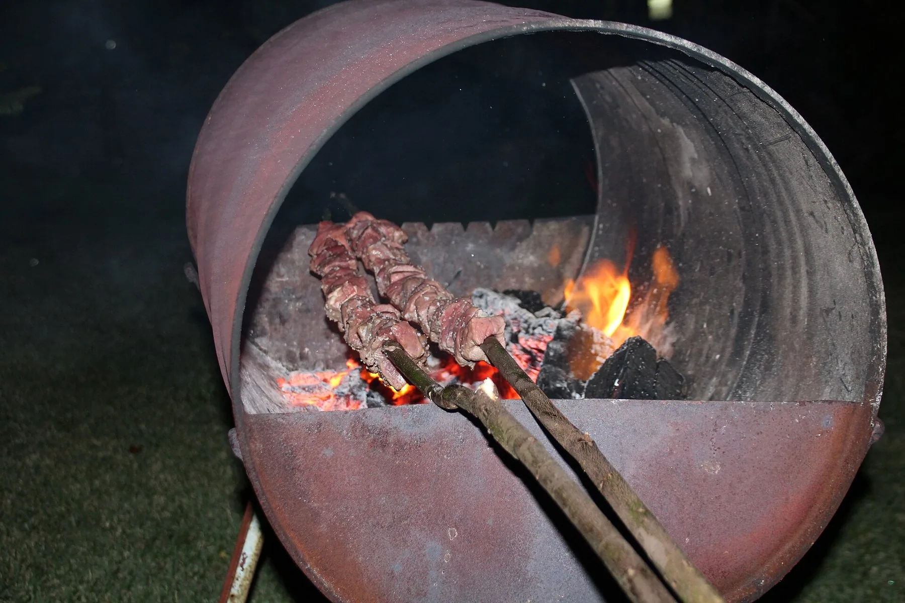 Espetada med storfekjøtt på laurbærspyd griller over glødende kull i en tønne gjort om til grill på Madeira
