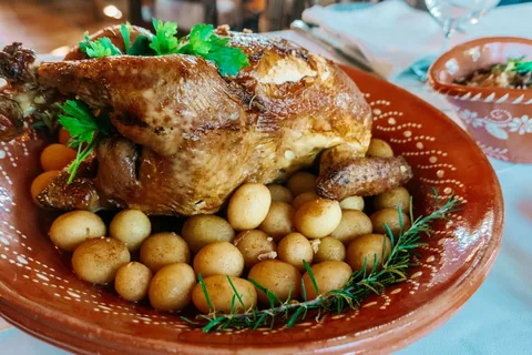 Helstekt kylling med småpoteter og urter på et dekorert portugisisk leirfat