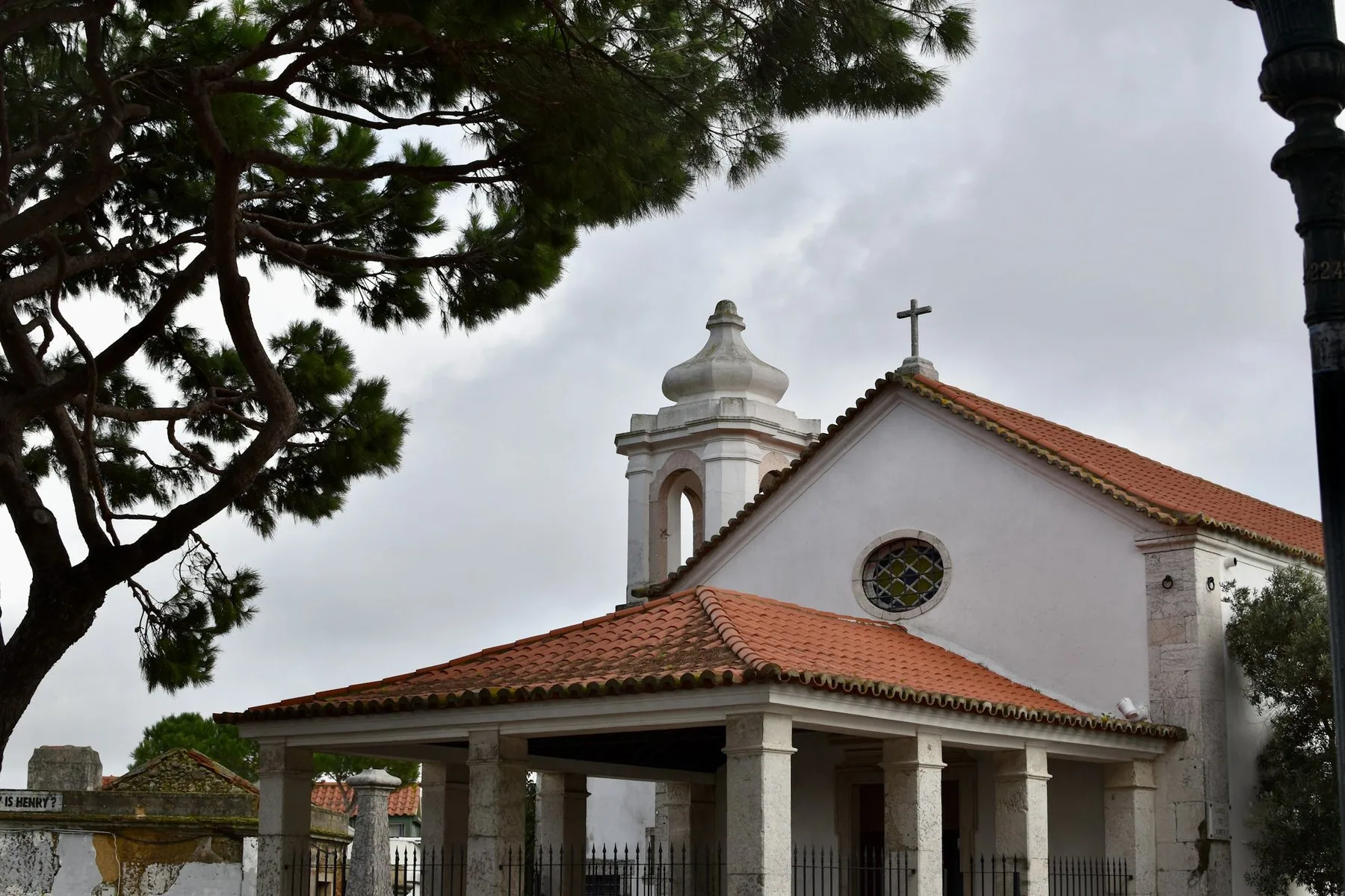 Hvit kirke med rødt tegltak og kors på gavlen mot blå himmel i Lisboa
