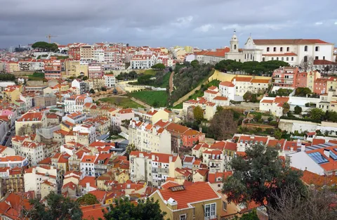 Tett bebyggelse med røde tak og lyse fasader i en åsside i Lisboa en lett overskyet dag