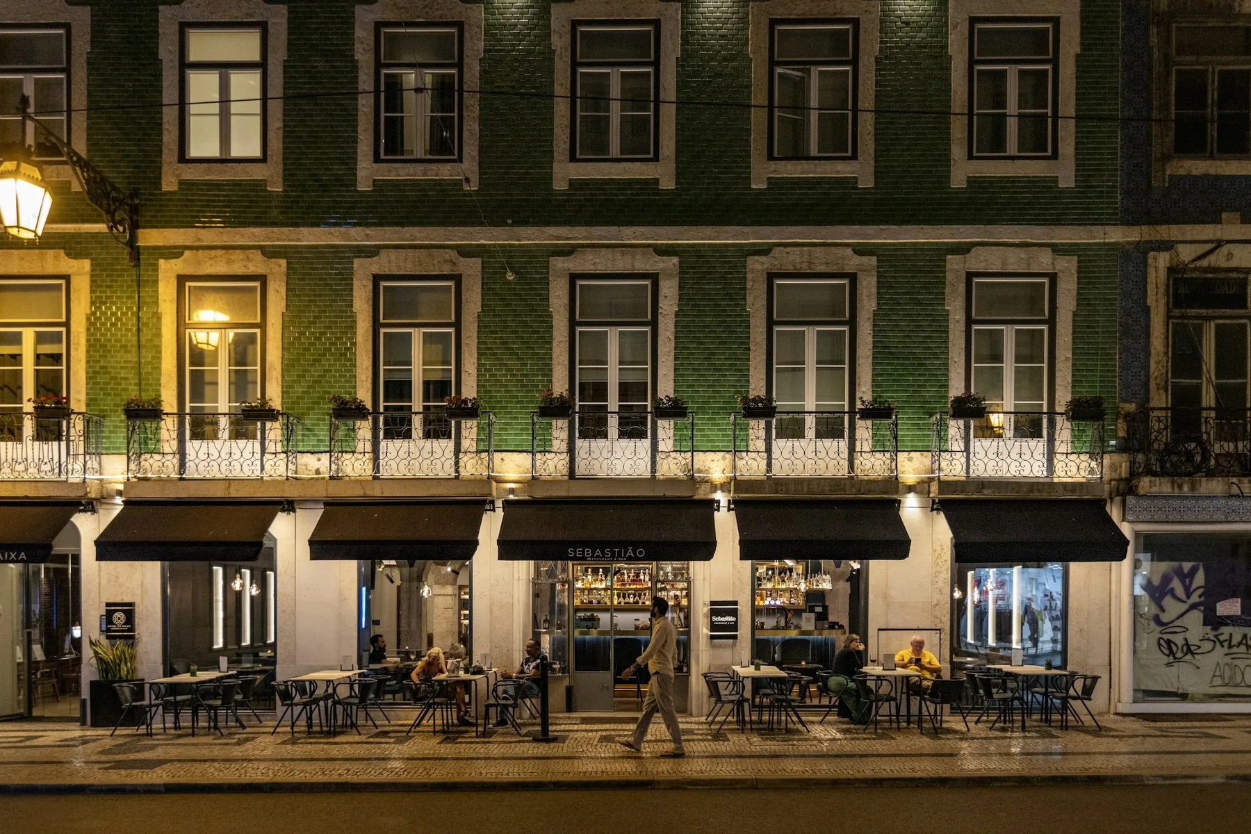 Restaurantbord og fasader i en gate i Lisboa sentrum, der det er kort vei til butikk og marked