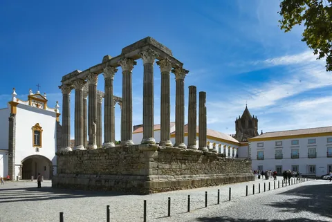 Hvitkalket bygning med søyler og buer på en åpen plass i Evora i Alentejo