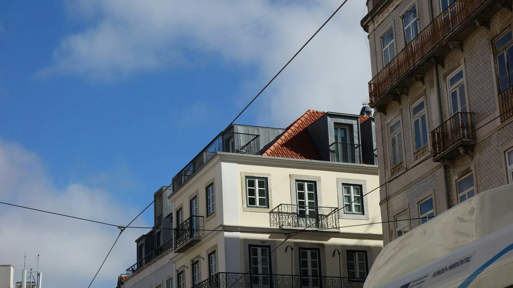Leilighetsbygg med balkonger og takterrasse i bydelen Graca i Lisboa under blå himmel