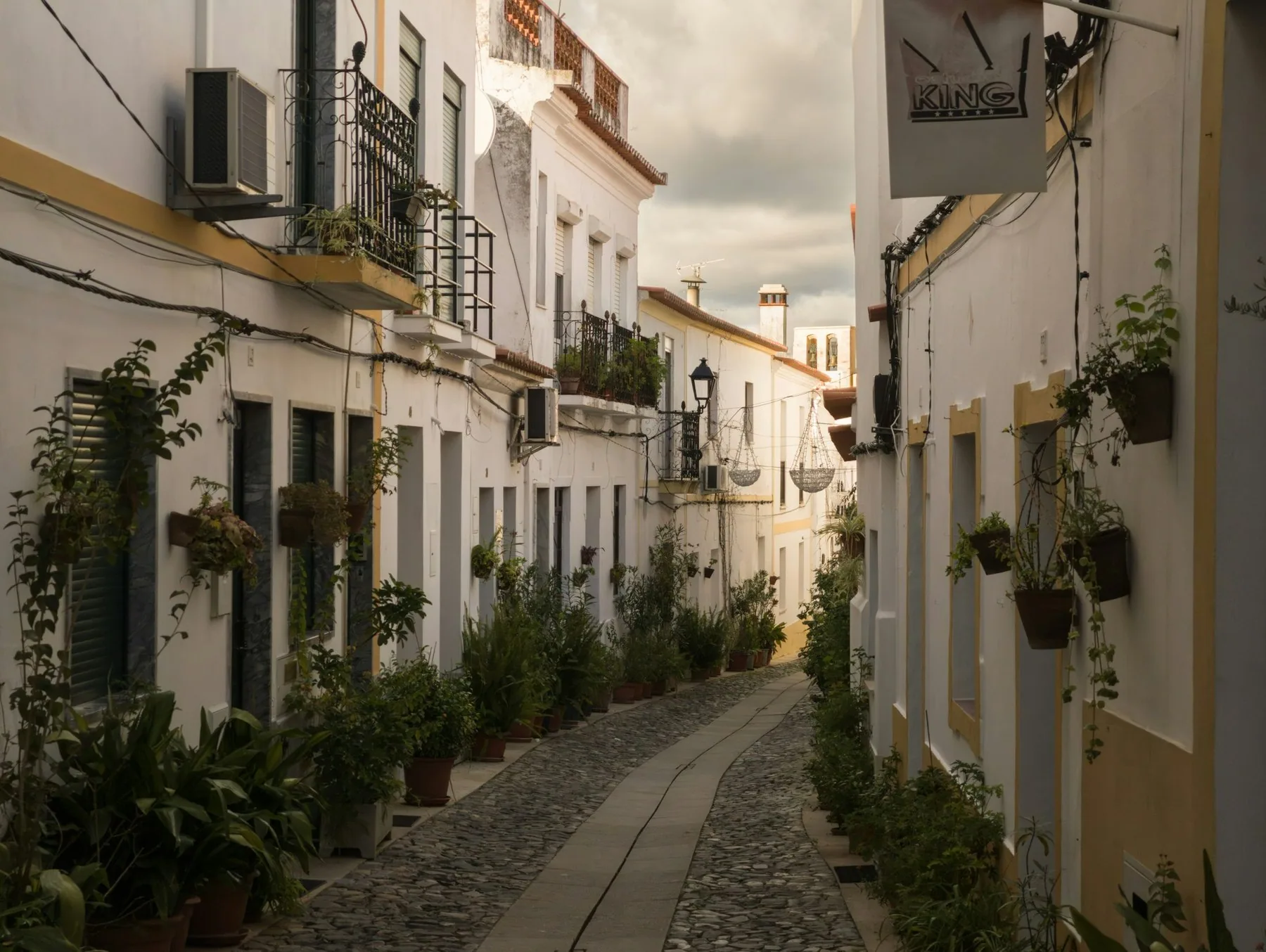 Smal brosteinsgate med hvitkalkede hus og potteplanter i landsbyen Moura i Alentejo