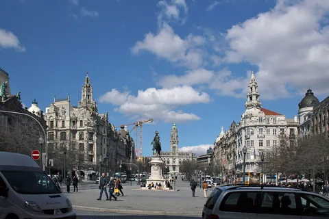 Avenida dos Aliados i Porto med rytterstatuen av Dom Pedro IV, klokketårn og staselige fasader under blå himmel