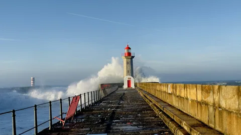 Fyrtårnet Felgueiras på moloen i Foz do Douro med bølger som slår over kaia