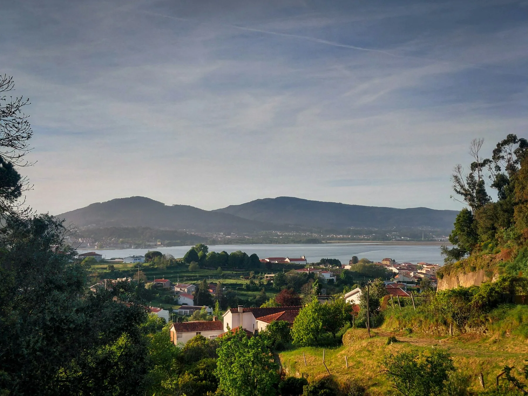 Utsikt fra Vilarelho ved Caminha over hus, grønne jorder og Minho-munningen mot åsene på galicisk side