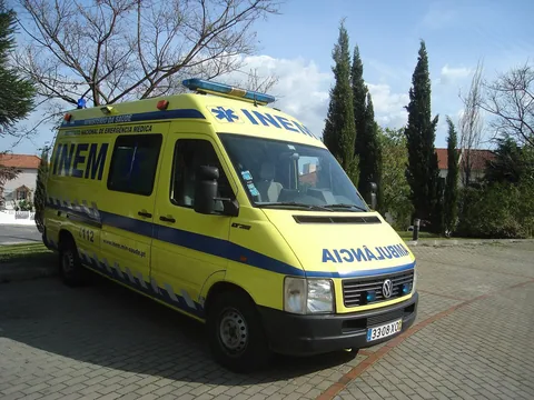INEM-ambulanse sett forfra med nodnummeret 112 på siden, parkert under trær i Portugal