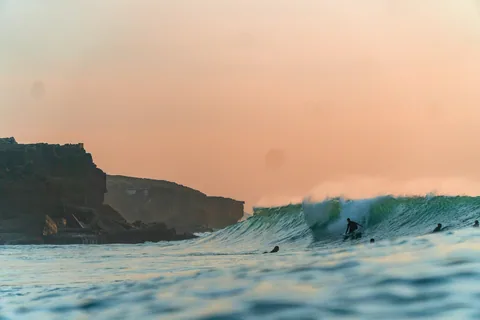 Surfere rir bolgene utenfor Ericeira på den portugisiske vestkysten