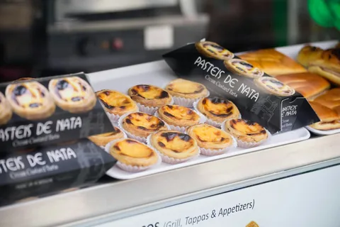 Pastéis de nata stilt ut på brett i vinduet til et portugisisk bakeri