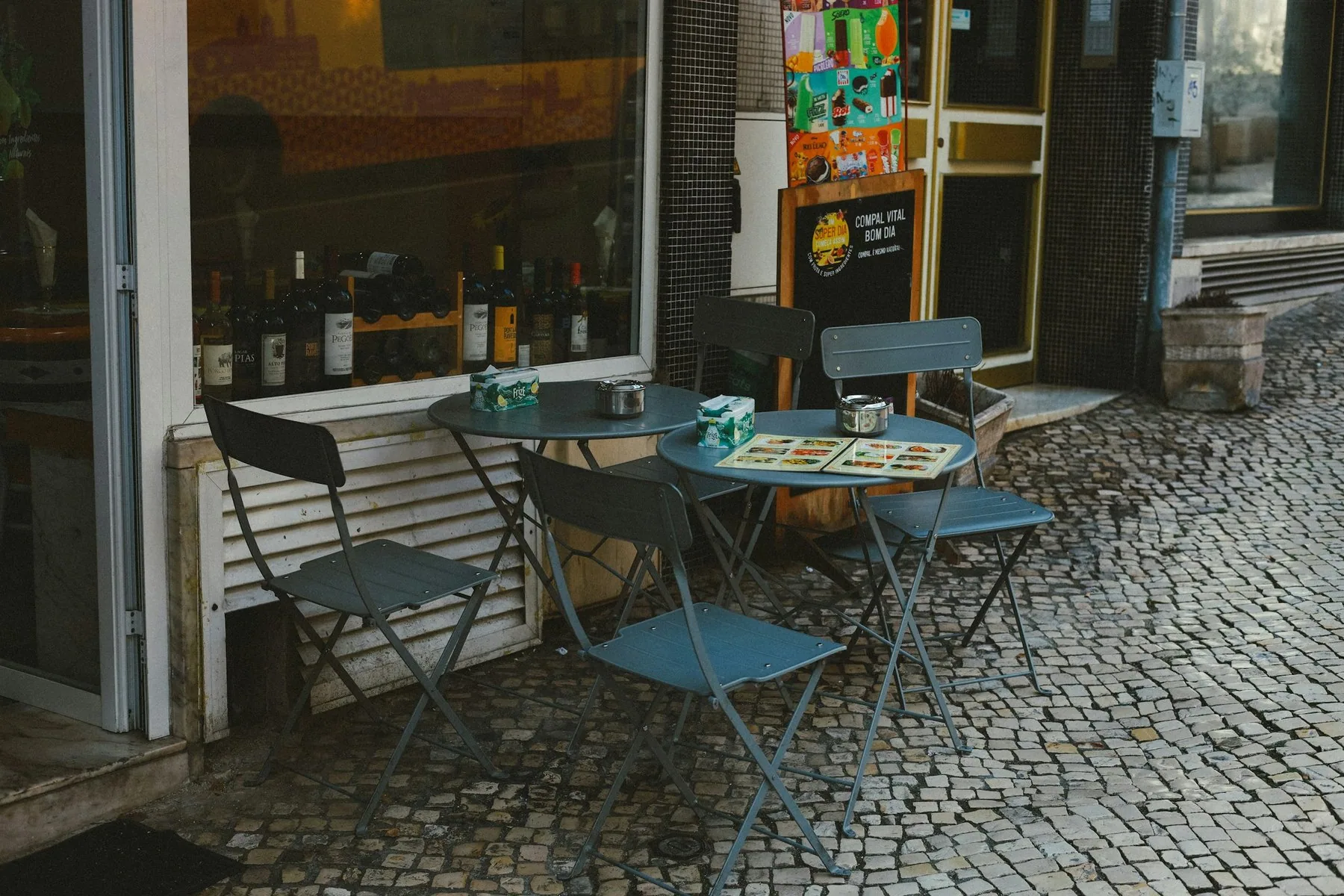 Bord og stoler på fortauet utenfor en tradisjonell restaurant i Lisboa