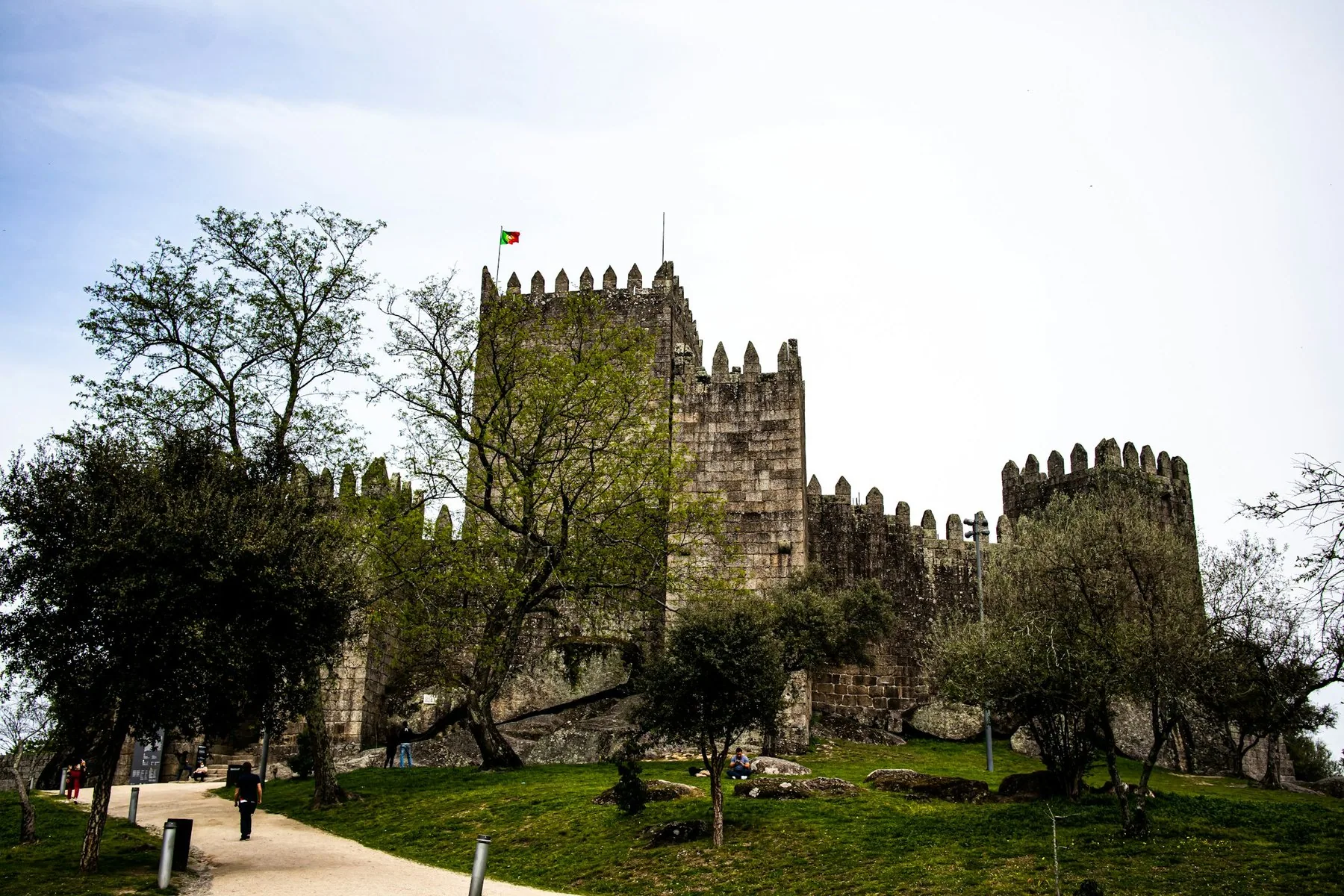 Middelalderborgen i Guimarães med steintårn bak grønne trær og gressplen
