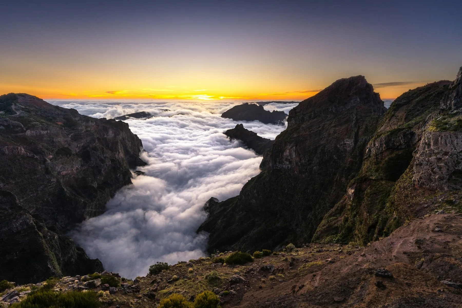Solnedgang over et hav av skyer mellom mørke, bratte fjelltopper på Madeira