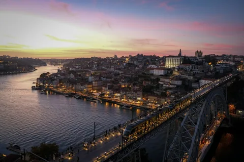 Porto i solnedgang med Dom Luis I-broen over Douro-elven og bylysene som tennes