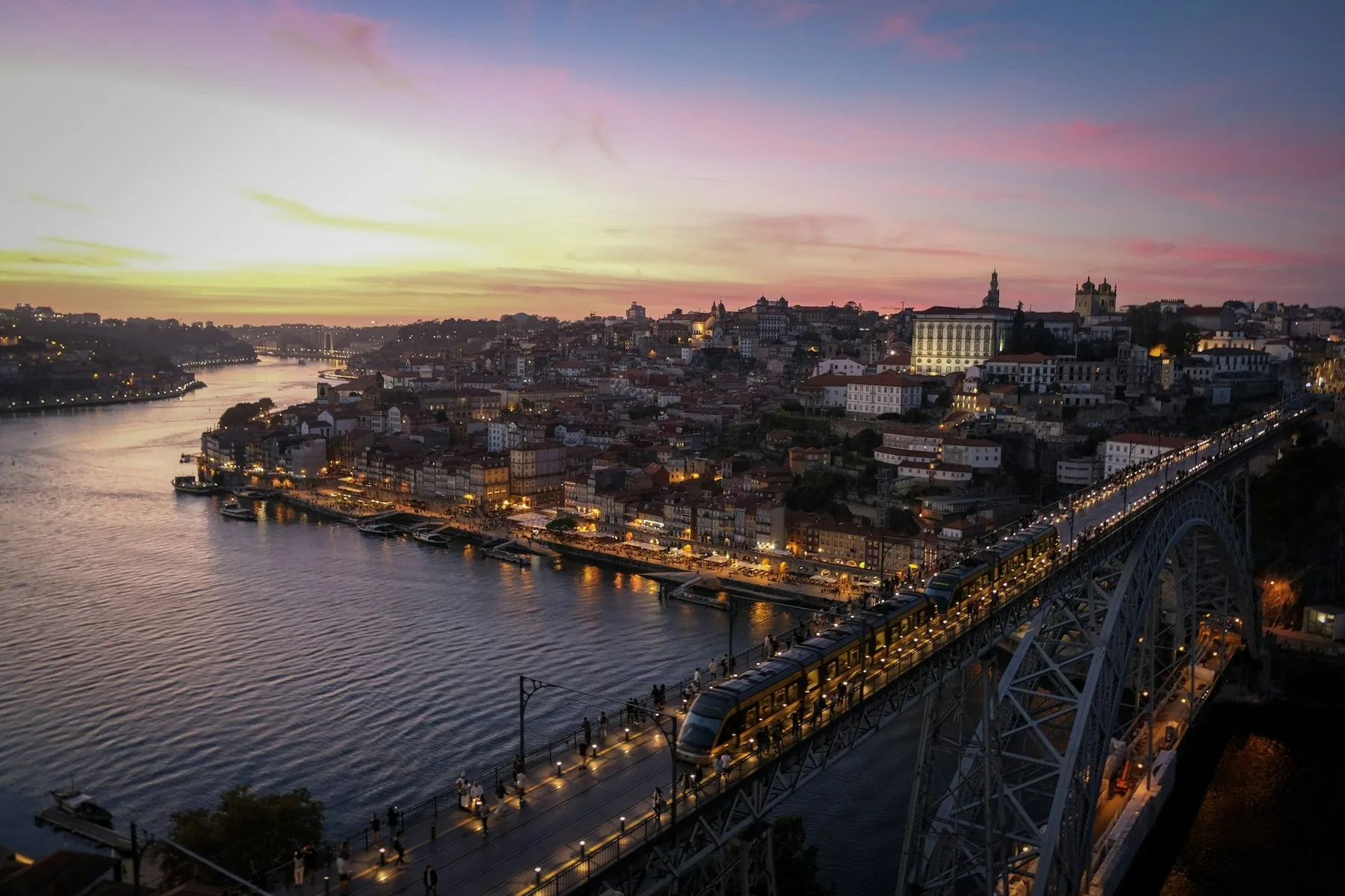 Porto i solnedgang med Dom Luis I-broen over Douro-elven og bylysene som tennes