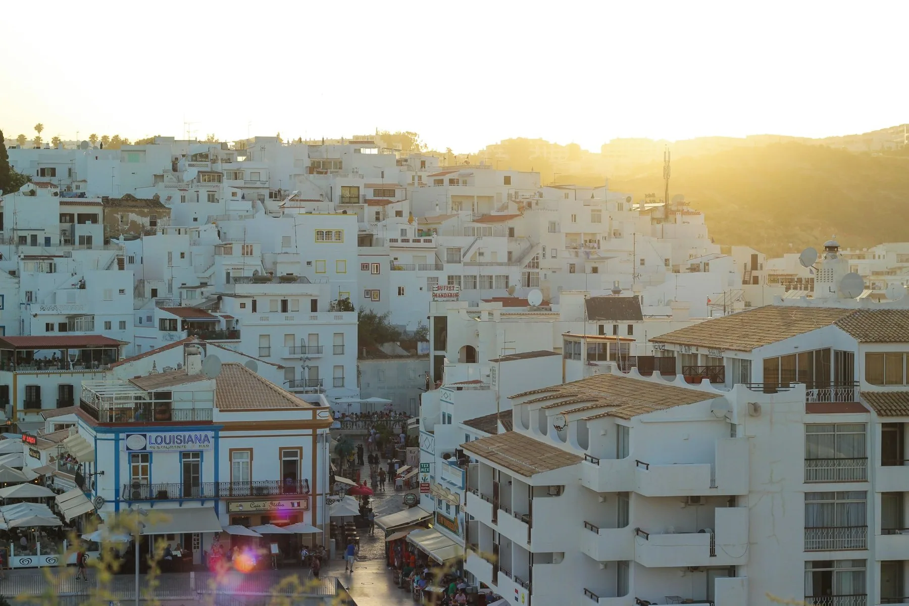 Hvite hus og leilighetsbygg tett i tett i sentrum av Albufeira i lavt kveldssollys