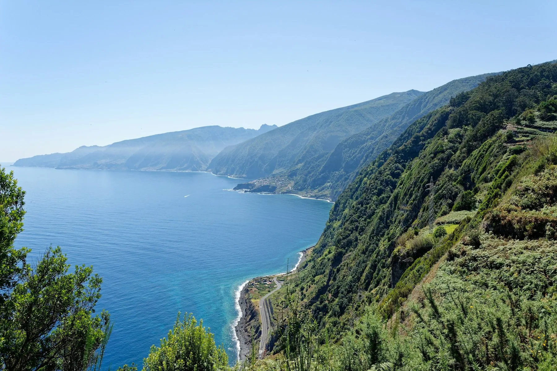 Grønne, bratte fjellsider stuper i blått hav langs kysten av Madeira, sett fra Eira da Achada