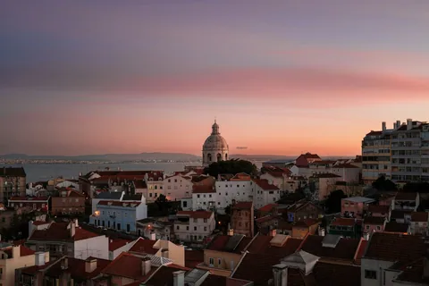 Takene i Lisboa med en hvit kuppel og Tejo i bakgrunnen under en rosa solnedgangshimmel