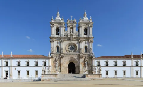 Den barokke hovedfasaden på klosteret i Alcobaça med to klokketårn og hvite fløyer på hver side