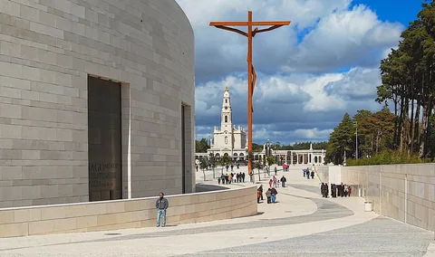 Den store plassen ved helligdommen i Fatima med det høye korset, basilikaens tårn og skyer over