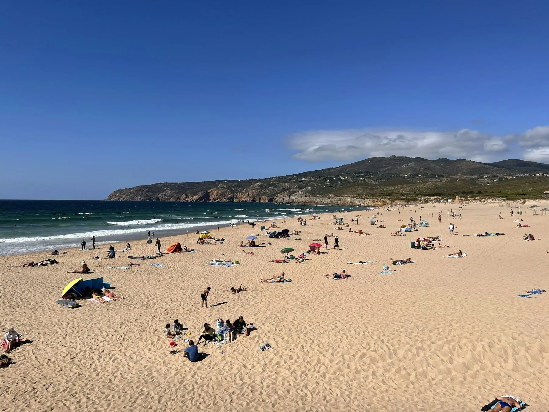 Praia do Guincho utenfor Cascais en sommerdag, med folk på sanden og blå himmel
