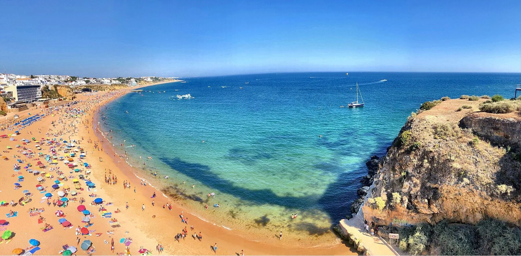 Bystrendene Peneco og Pescadores i Albufeira sett fra klippen, med turkist vann og hvite hus langs bukta