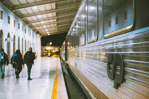 Reisende går langs et CP-tog på perrongen på Santa Apolonia-stasjonen i Lisboa