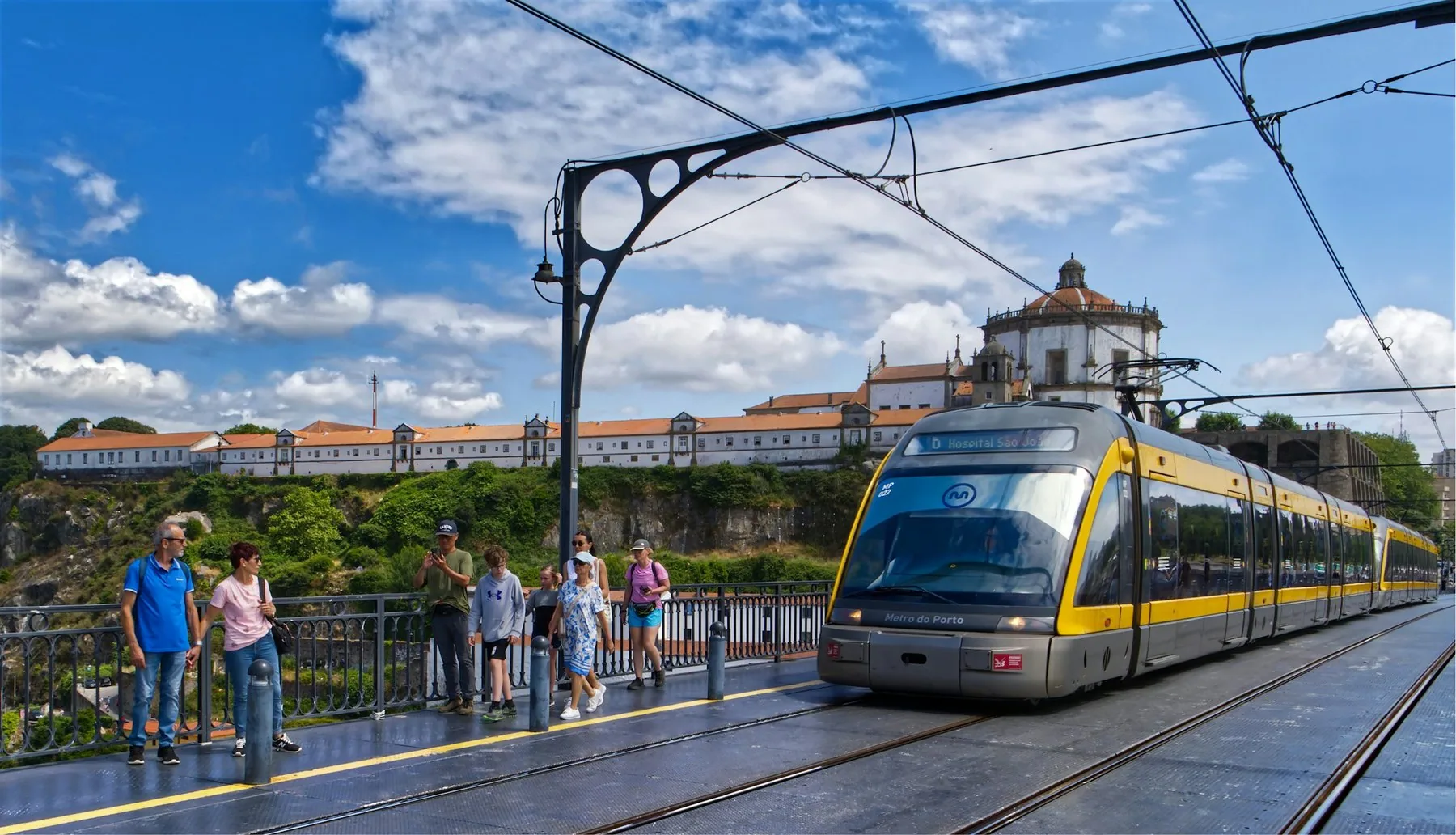 Gult metrotog krysser øvre dekk på Dom Luis I-broen i Porto med klosteret i bakgrunnen