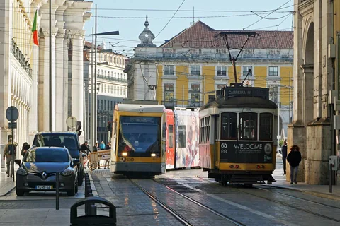 En moderne gul trikk på linje 15 og en gammel trikk på linje 25 side om side i Rua do Arsenal i Lisboa