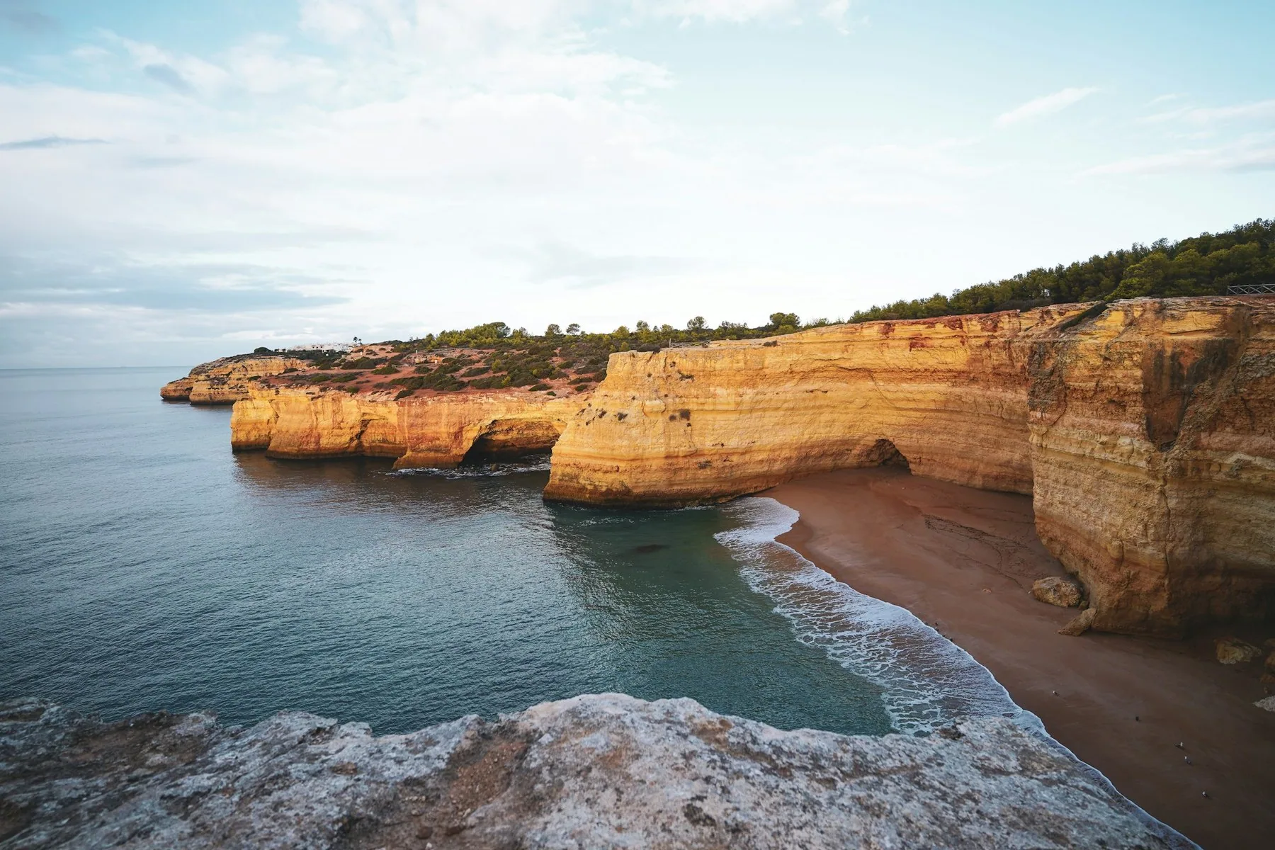 Solbelyste klipper over det blå havet ved Carvoeiro i Algarve en skyfri dag