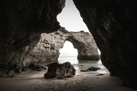 Gyllen kalksteinsklippe stuper ned i turkist hav ved Praia da Marinha i Algarve